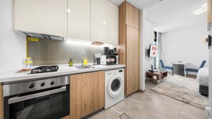 A modern kitchen with a stove, microwave, and washing machine. - StayShort - Studio in Business Bay Sleeps 2 with Burj Views! (Dubai)