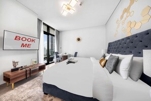 Una habitación de hotel moderna con una cama grande, un escritorio y vistas a la ciudad.