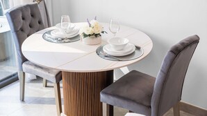 A round dining table with white plates, silverware, and glasses, set with a floral centerpiece. - StayShort - Studio in Business Bay Sleeps 2 with Burj Views! (Dubai)