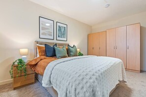 A bedroom with a bed, bedside tables, a wardrobe, and two framed pictures on the wall. - #109 Modern 3-Bed Home in Moseley (Balsall Heath)