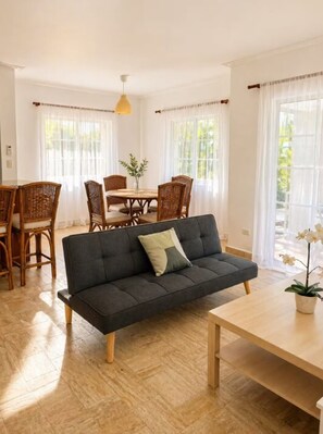 Una sala moderna con un sofá, una mesa de comedor, sillas y una planta en maceta.