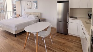 A modern bedroom with a bed, bedside table, and a small table with chairs. - Just Renovated Marine Surf Corner Unit with Free Parking! (Honolulu)