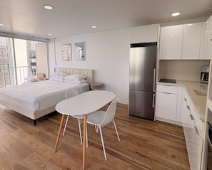 A modern bedroom with a bed, bedside table, and a small table with chairs. - Just Renovated Marine Surf Corner Unit with Free Parking! (Honolulu)