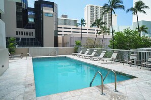 A swimming pool with lounge chairs and a view of surrounding buildings. - Just Renovated Marine Surf Corner Unit with Free Parking! (Honolulu)