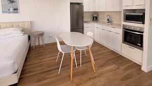 A compact kitchen with white cabinets, a refrigerator, a microwave, and an oven. - Just Renovated Marine Surf Corner Unit with Free Parking! (Honolulu)