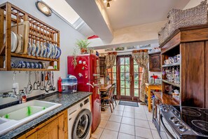 A kitchen with a washing machine, a red refrigerator, and a dining area with a table and chairs. - Host Stay The 1890 Petersfield Retreat (Cambridge)