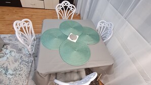 A dining area with a table set for four, surrounded by white chairs. - Bright & Cosy Apartment with Sunset View in Bucharest (București)
