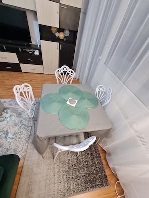 A dining area with a table set for four, surrounded by white chairs. - Bright & Cosy Apartment with Sunset View in Bucharest (București)