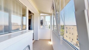A narrow balcony with a view of buildings, a door, and a window with blinds. - Bright & Cosy Apartment with Sunset View in Bucharest (București)