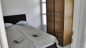 A bed with a headboard, two pillows, and a blanket rolled up at the foot.