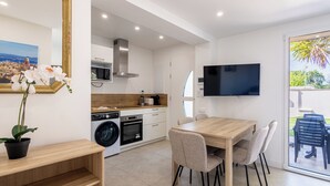 A modern kitchen with appliances, a dining area with chairs, and a TV mounted on the wall. - (106) A la Joie de vivre 1 (Cannes)