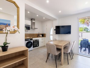 A modern kitchen with appliances, a dining area with chairs, and a TV mounted on the wall. - (106) A la Joie de vivre 1 (Cannes)