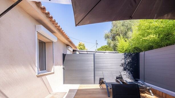 A patio with a wooden deck, a black chair, and a grey gate. - (106) A la Joie de vivre 1 (Cannes)