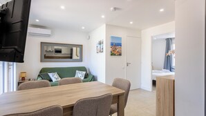 A modern living room with a dining table, sofa, and a flat-screen TV mounted on the wall. - (106) A la Joie de vivre 1 (Cannes)