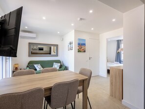 A modern living room with a dining table, sofa, and a flat-screen TV mounted on the wall. - (106) A la Joie de vivre 1 (Cannes)