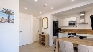 A modern kitchen with white cabinets, a black refrigerator, and a wooden dining table with chairs. - (106) A la Joie de vivre 1 (Cannes)