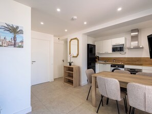 A modern kitchen with white cabinets, a black refrigerator, and a wooden dining table with chairs. - (106) A la Joie de vivre 1 (Cannes)