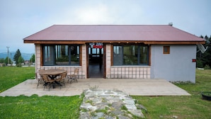 A small building with a metal roof, large windows, and a wooden deck with a table and chairs. - Zifin Hotel (Dereli)
