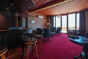 A hotel lobby with a bar area, seating, and a large window offering a view.