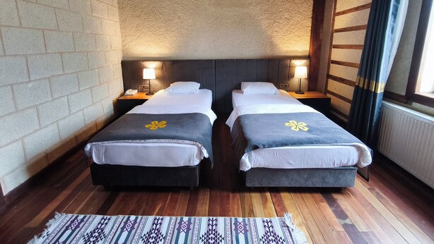 A double room with two beds, a wooden ceiling, brick walls, and a patterned rug. - Zifin Hotel (Dereli)