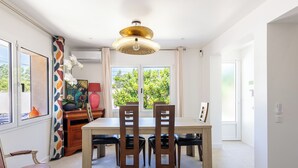 A dining area with a table, chairs, a decorative lamp, and a view of greenery outside. - (107) A la Joie de vivre 2 (Cannes)
