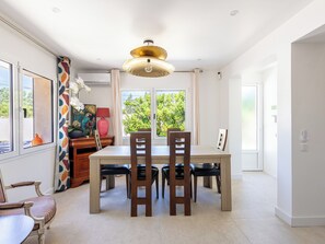 A dining area with a table, chairs, a decorative lamp, and a view of greenery outside. - (107) A la Joie de vivre 2 (Cannes)
