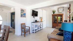 A spacious living area with a television, a cabinet with glass doors, a sofa, and a dining table. - (107) A la Joie de vivre 2 (Cannes)