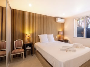 Ein Hotelzimmer mit einem Bett, Nachttischen, einem Sessel und einem Fenster mit gestreifter Wand.