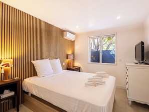 A hotel room with a bed, bedside lamps, a TV, and a window with a view of trees. - (107) A la Joie de vivre 2 (Cannes)