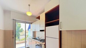 A compact kitchen with a gas stove, sink, and a refrigerator. - Spacious studio, terrace, sea view - 2 guests (Menton)