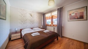 A hotel room with a bed, bedside tables, a lamp, a window with curtains, and a painting on the wall. - Apartamenty Sun&Snow VIVA MARIA SPA II (Zakopane)