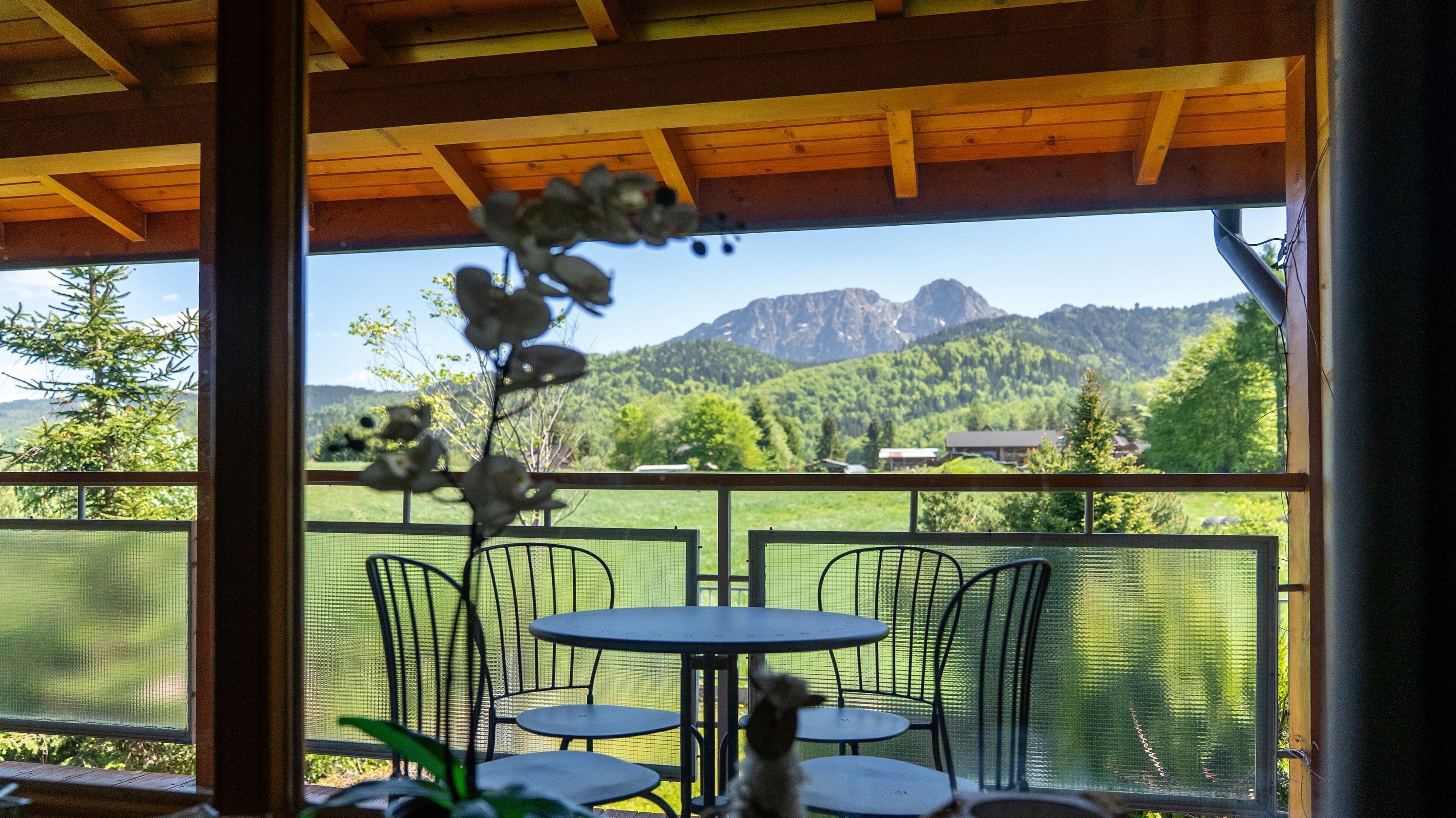 A covered outdoor seating area with a view of mountains and greenery.