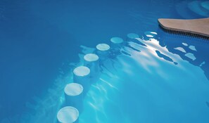 Una piscina azul cristalina con objetos flotantes circulares y un borde con azulejos.