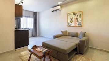 A modern living room with a sofa, a small wooden table, and a kitchen area in the background.