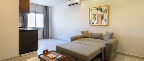 A modern living room with a sofa, a small wooden table, and a kitchen area in the background.