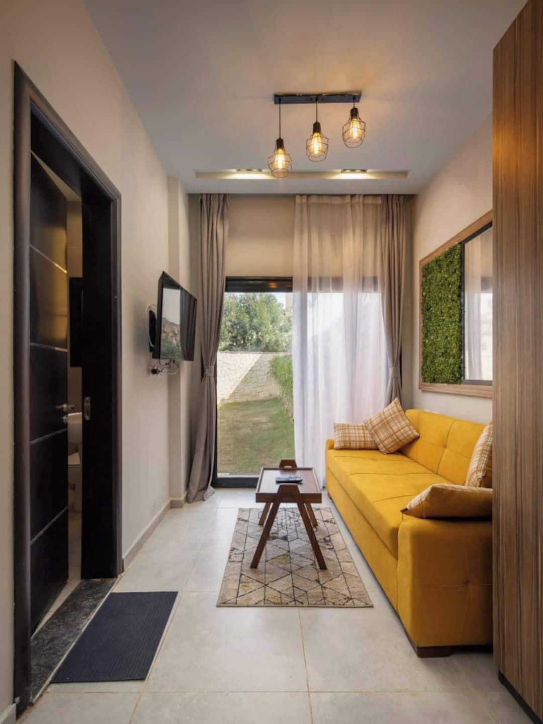 A modern living room with a sofa, a coffee table, and a TV mounted on the wall.