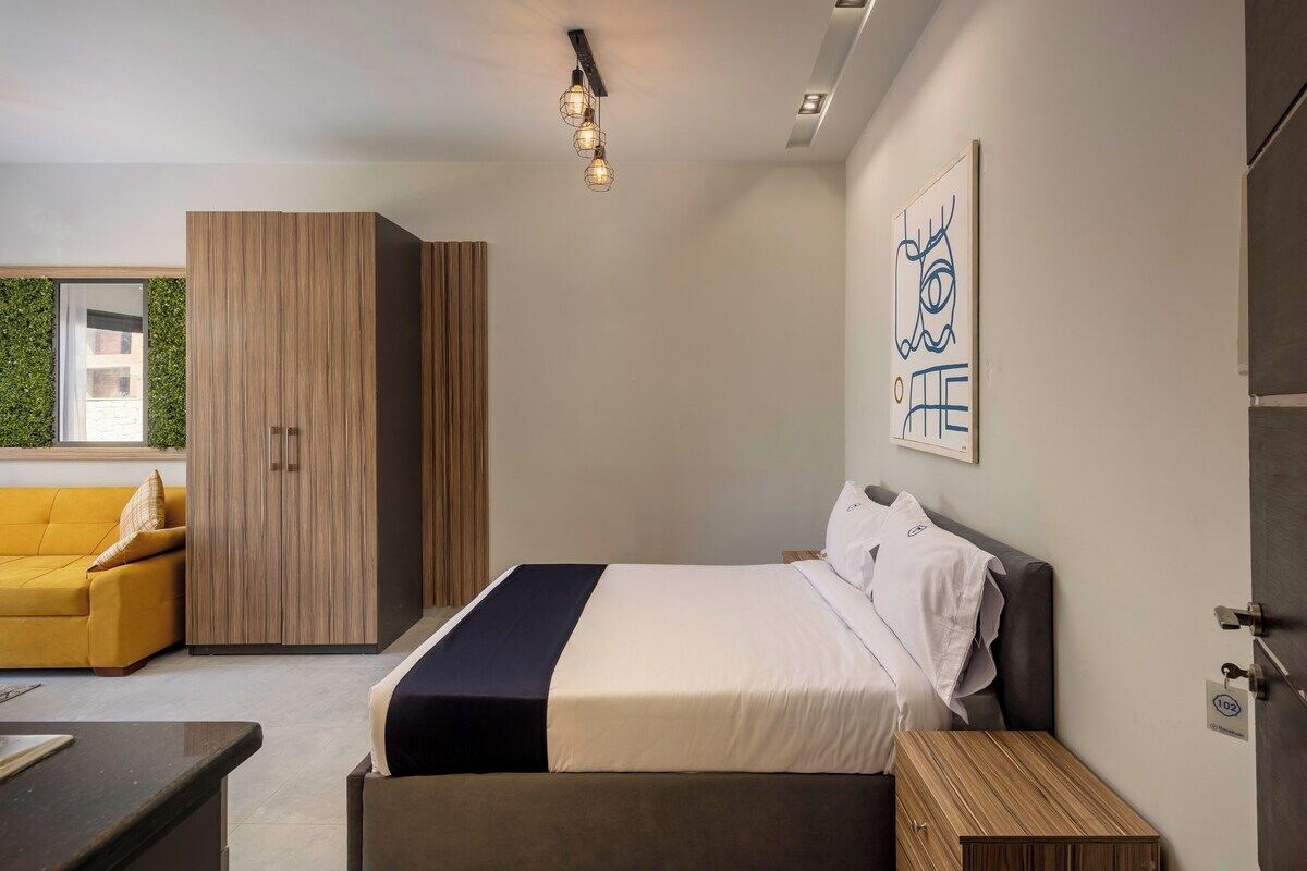 Une chambre d’hôtel moderne équipée d’un lit, d’un canapé, d’une armoire et d’un bureau.