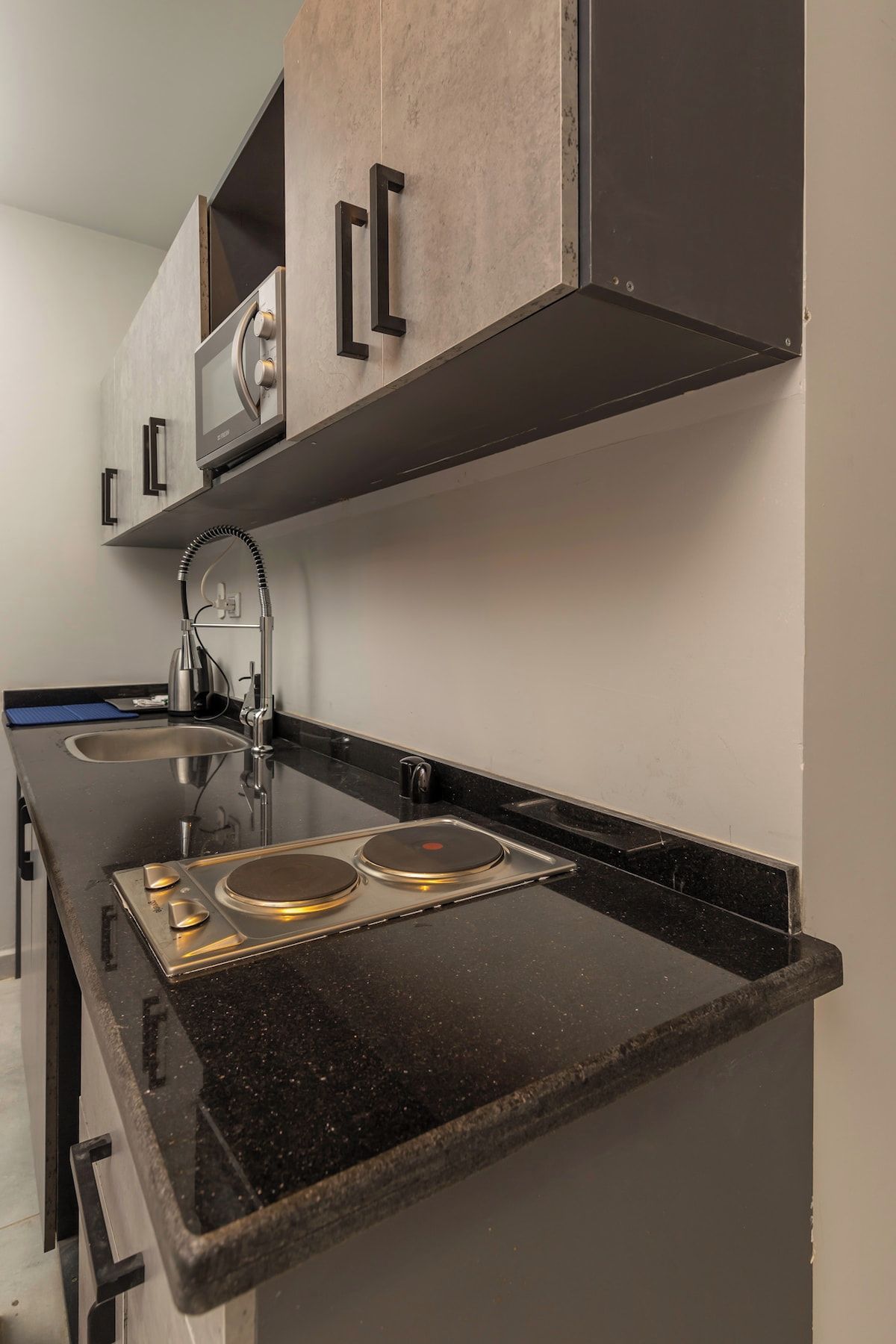 A kitchen with a black countertop, stainless steel appliances, and wooden cabinets.