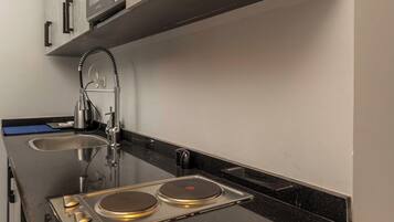 A kitchen with a black countertop, stainless steel appliances, and wooden cabinets.