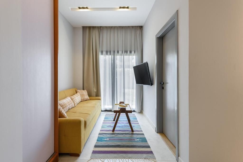 A modern living room with a sofa, a small table, and a television mounted on the wall.