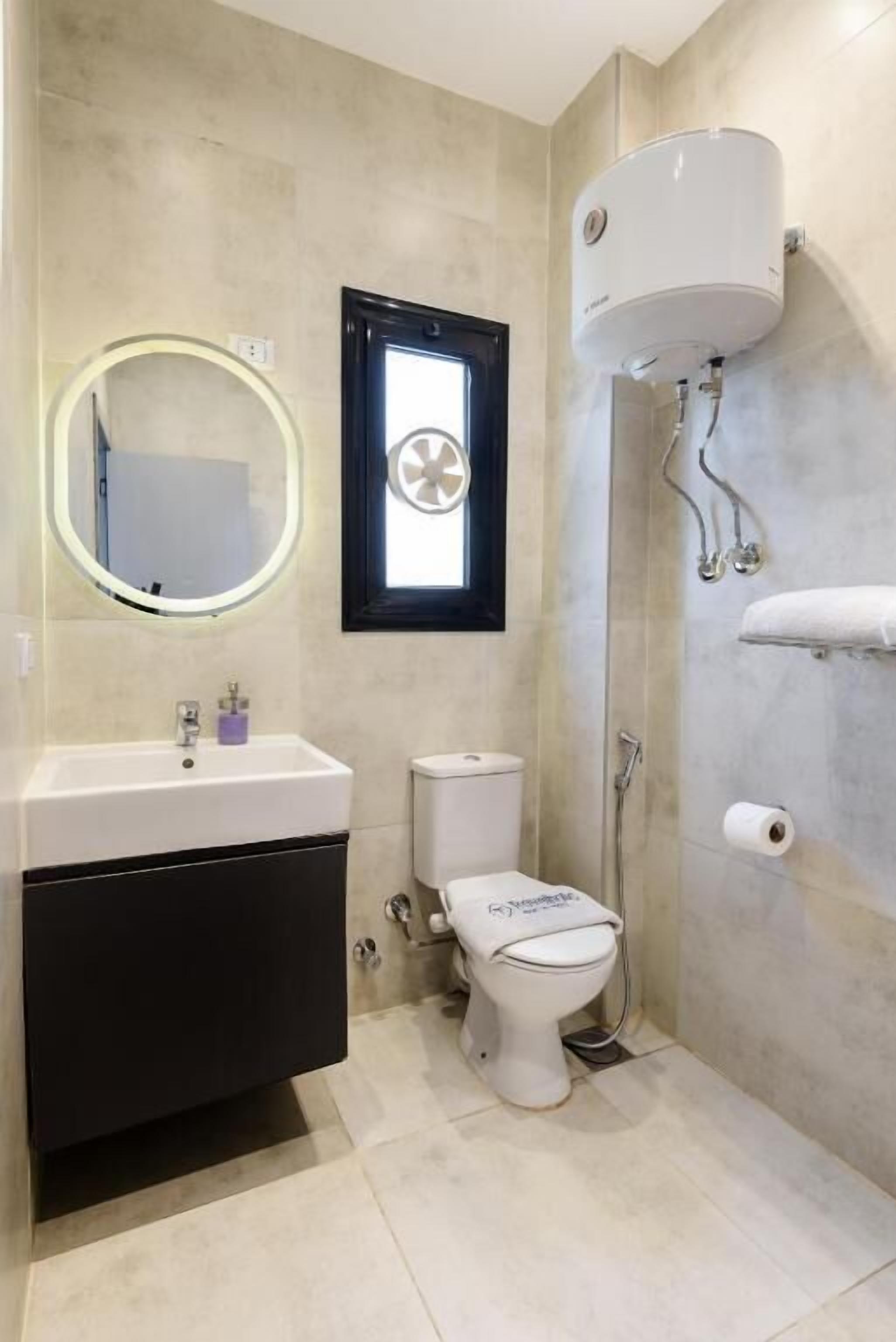 Un baño con inodoro, lavamanos, espejo y ventana.