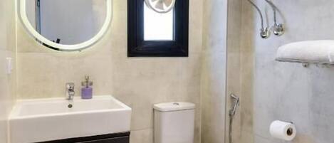 Un baño con inodoro, lavamanos, espejo y ventana.