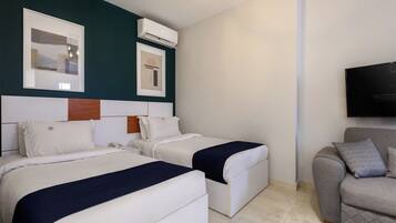 Habitación de hotel con dos camas, un sofá, un televisor de pantalla plana y obras de arte en las paredes.