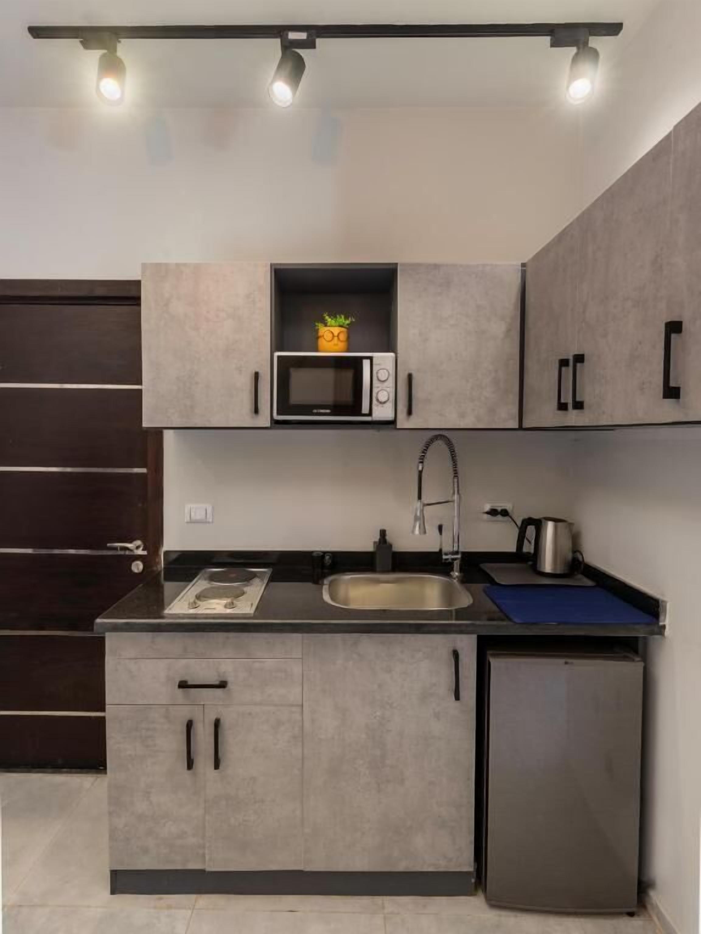 A compact kitchen with a microwave, sink, and stainless steel refrigerator.