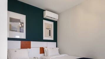 A hotel room with two beds, a ceiling light fixture, and an air conditioning unit.