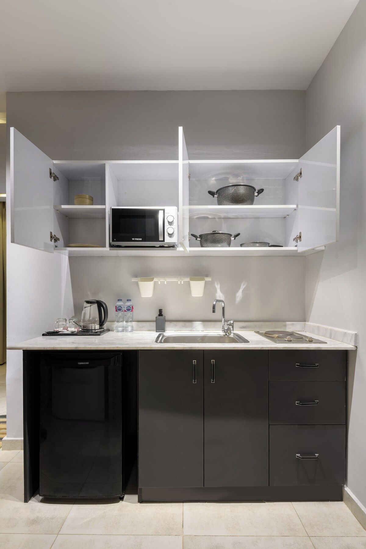Una cocina moderna con microondas integrado, hervidor y pileta.
