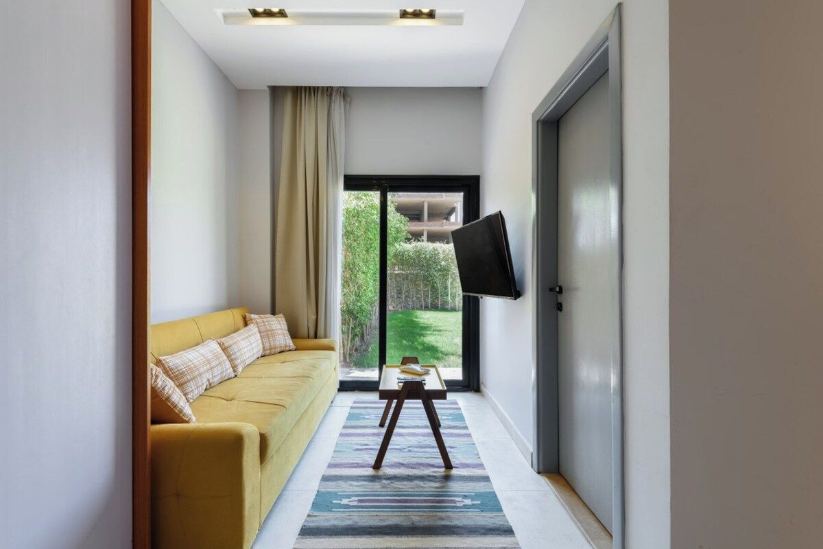 Un salon moderne avec un canapé, une table basse et un téléviseur à écran plat fixé sur une porte coulissante.