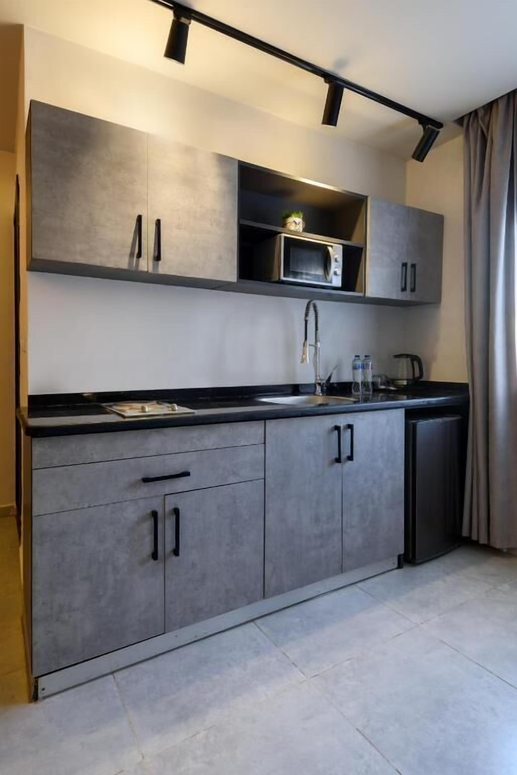 Een moderne keuken met grijze kastjes, een magnetron en een spoelbak.
