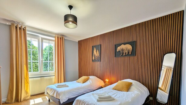 Une chambre d’hôtel avec deux lits, une fenêtre avec des rideaux, une lampe sur pied et un miroir.