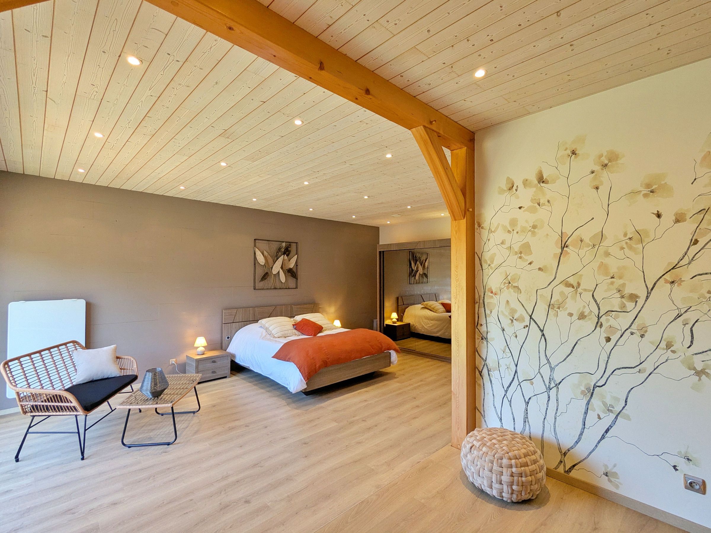 A bedroom with a bed, a chair, a small table, and a decorative wall.